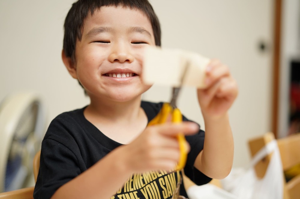 はさみで紙を切って工作を楽しむ子ども
