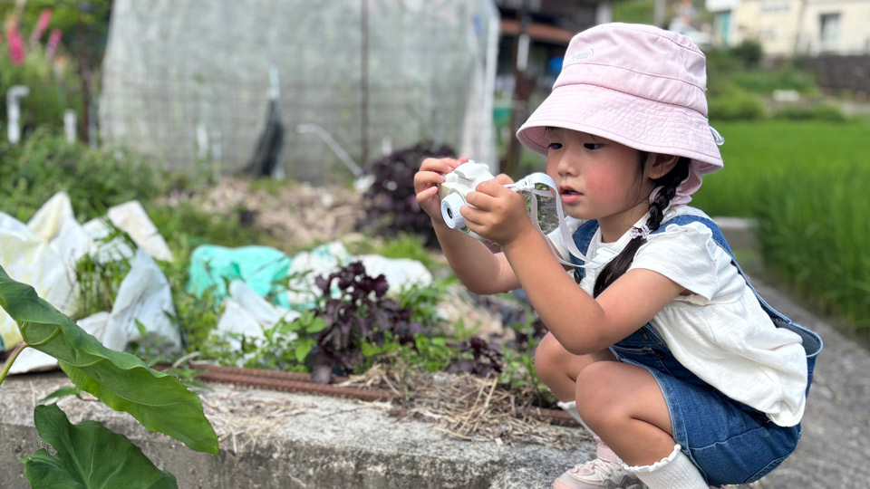 植物の観察をしながらカメラで撮影する子ども